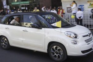 La Fiat 500L rappresenta una scelta piuttosto ordinaria rispetto ai veicoli da parata, sottolineando il carattere accessibile e il legame con la quotidianità